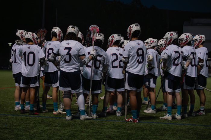 Men's Lacrosse team gathers in a huddle