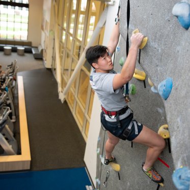 A student rock climbing in the gym