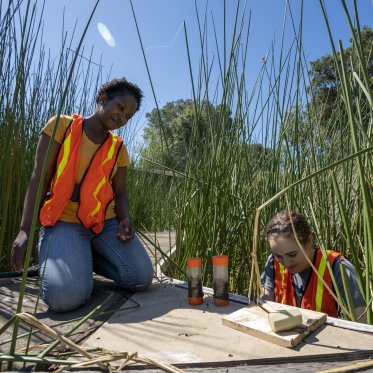 Research student and mentor collecting sediment in reservoir