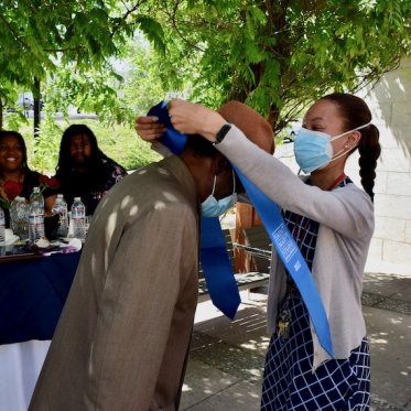 a girl helping a man to wear stole