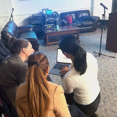 group of people discussing and one lady is showing something on the laptop