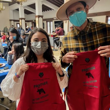 two people wearing masks and holding a red cloth