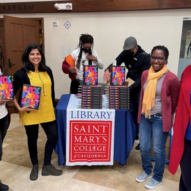 a group of people standing next to a table with books