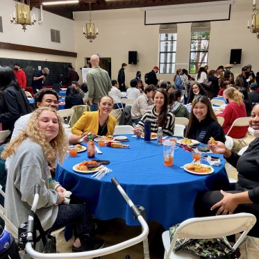 group of people standing around a table and eating