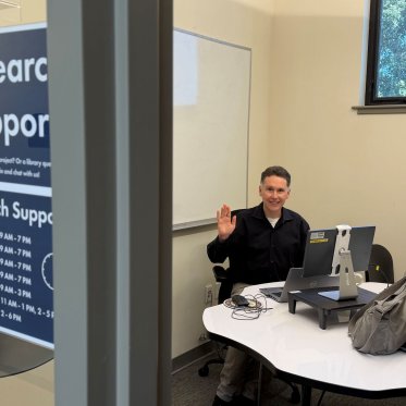 A librarian waving hello at the research support desk