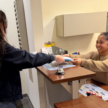 library staff member handing a checked out book to a student