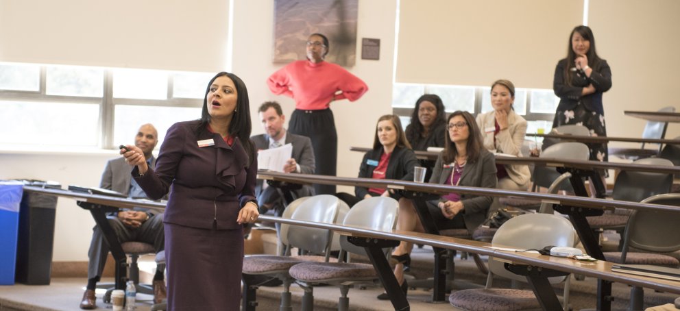 students sitting behind tables while a financial aid representative gestures to the white board