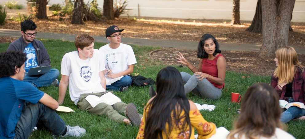 A professor teaching a Shakespeare class outside on the grass