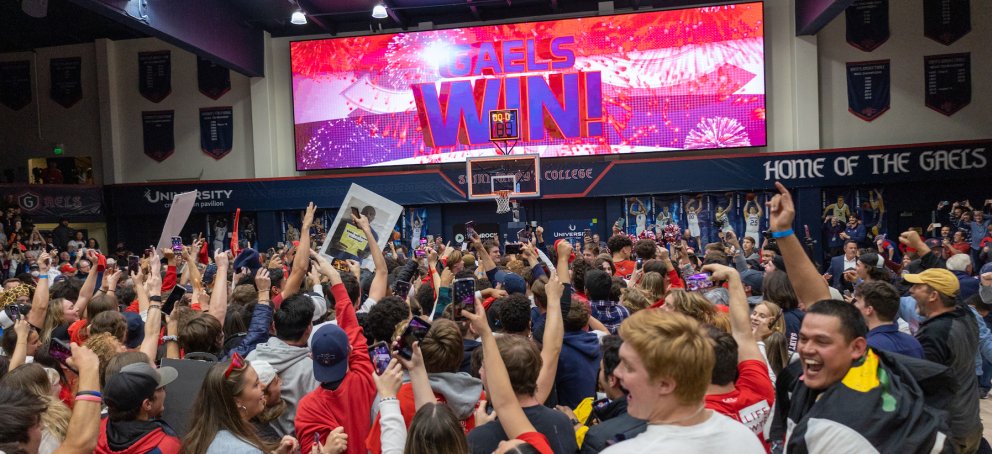A crowd of students cheering under a sign that says "Gaels Win"