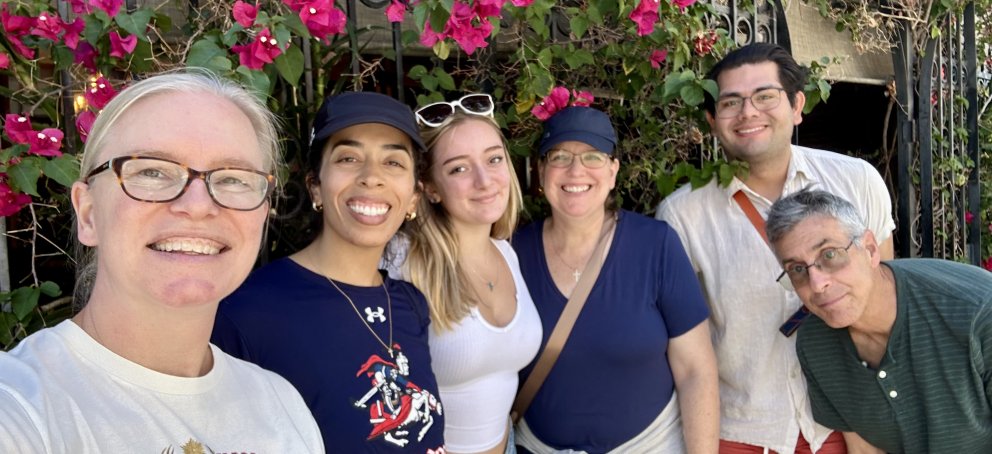Image of the staff of the Mission and Ministry Center in front of a fence with pink flowers