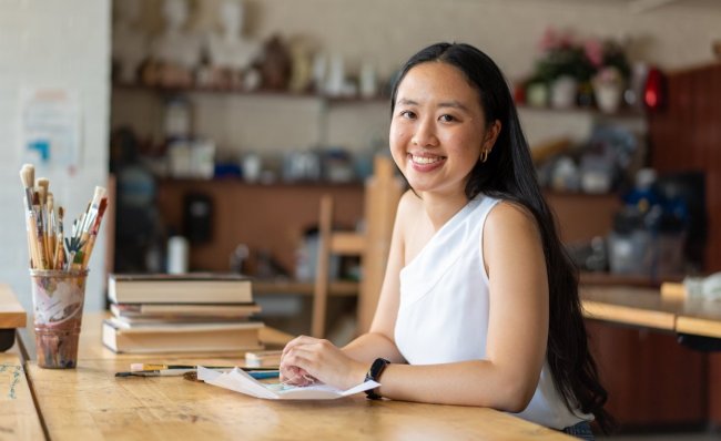 Gabrielle Ly at desk with paint brushes