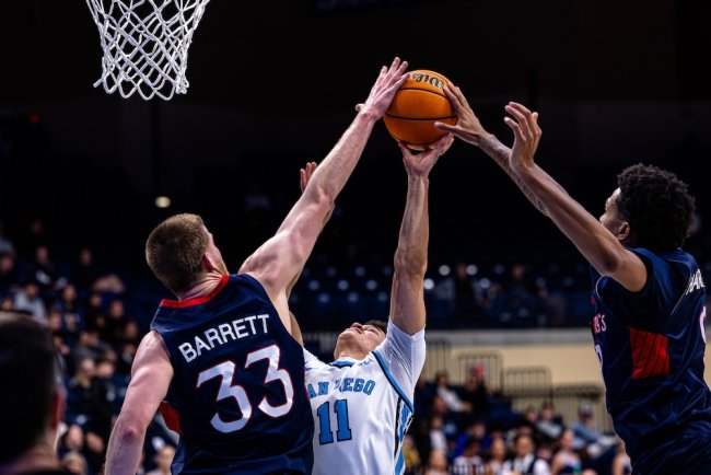 Men's basketball players Luke Barrett and Ashton Hardaway block a shot by a San Diego player in January 2025