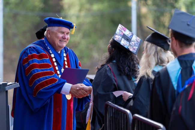 SMC President Roger Thompson presents students with diplomas at Graduate and Professional Studies Commencement