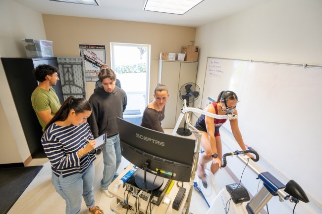 Students studying a person's oxygen levels while riding a stationary bicycle