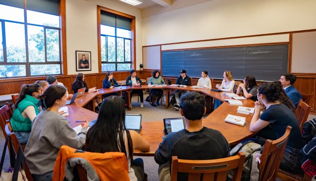 Prof. Emily Klein leads a Collegiate Seminar class which is seated around the table