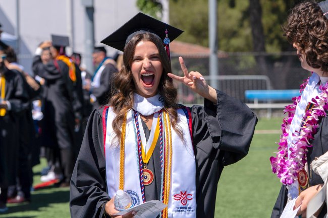 Female student making V sign at commencement 2026