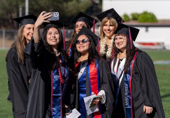 Six female graduate students taking a selfie at commencement 2026