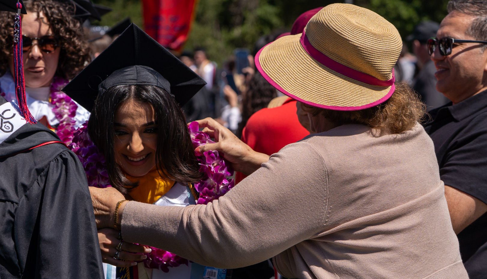 Woman puts lei on student at commencement