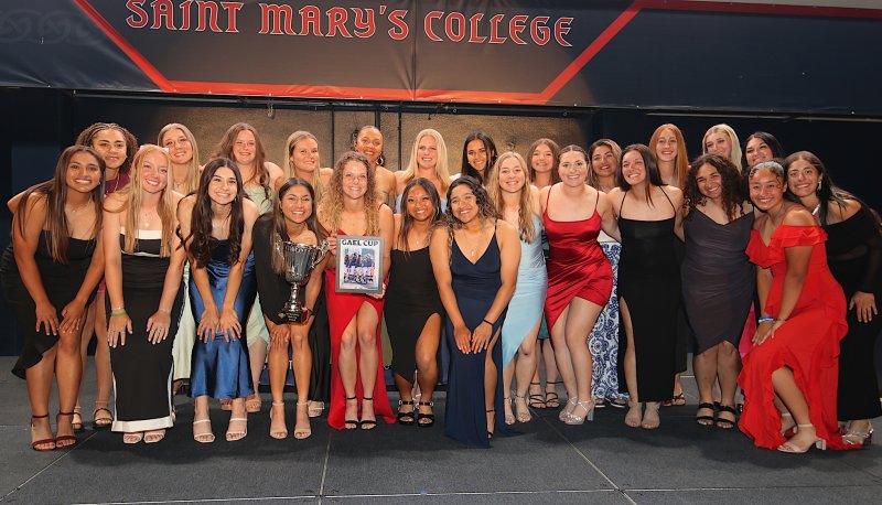 Women's softball team posing with Gael Cup award beneath Saint Mary's College banner, awards ceremony May 2024