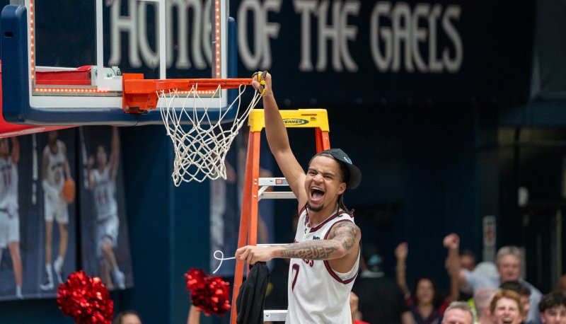 Basketball player Mikey Lewis cuts down the net after the Gaels win the WCC Title in February 2026