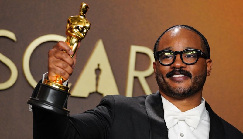 Ryan Coogler holding an Oscar aloft