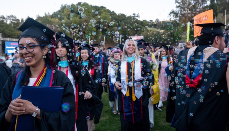 Students in graduation robes with bubbles in the air