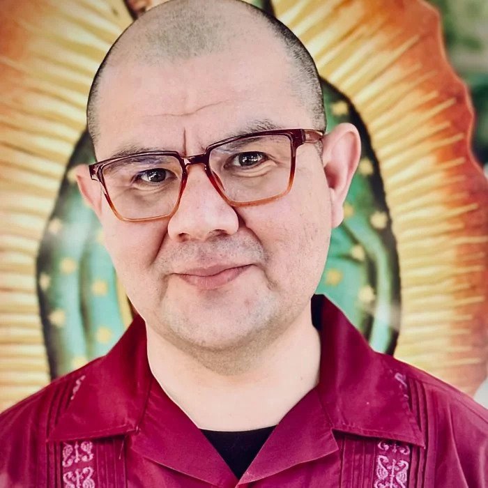 Headshot of Javier Hurtado behind a picture of the Virgen de Guadalupe