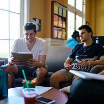 Students discussing an essay while sitting on sofas in the Writing Center.