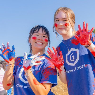 Two female students paint the SMC and smile at camera