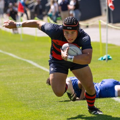 SMC Men's Rugby player runs with the ball past BYU defenders, April 2024