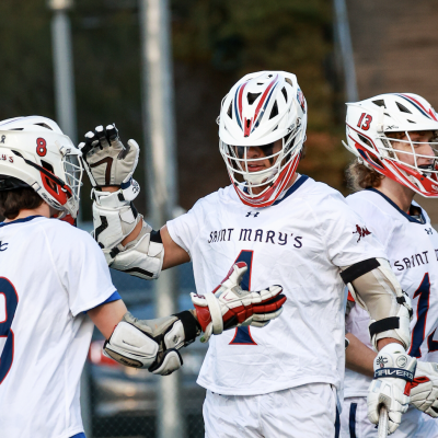 Men’s Lacrosse team members Tim Daly (No. 8), Dario Caccia (No. 4), and Hayden Bradley (No. 13) celebrate after scoring against UC Irvine in a match on the Recreational Turf Field last Spring. / Photo by Ashleen Rai ’26