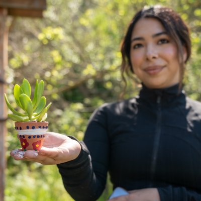 Student holding a succulent in a pot on Earth Day 2024