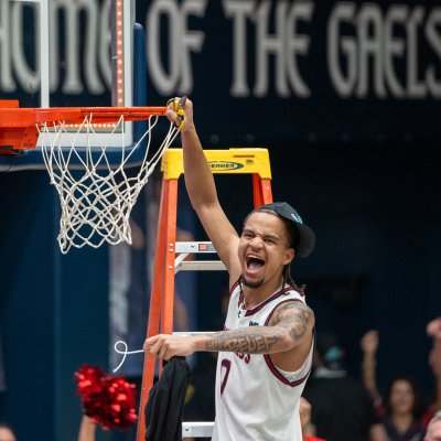 Basketball player Mikey Lewis cuts down the net after the Gaels win the WCC Title in February 2026