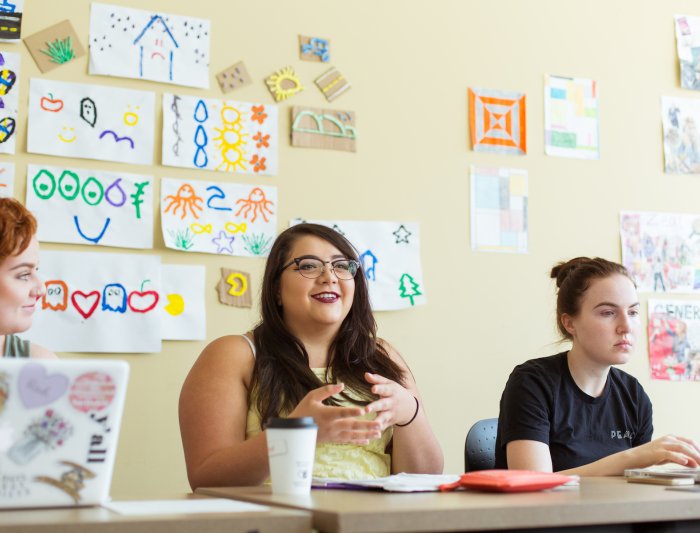 A student is sitting at a desk and talking to the professor