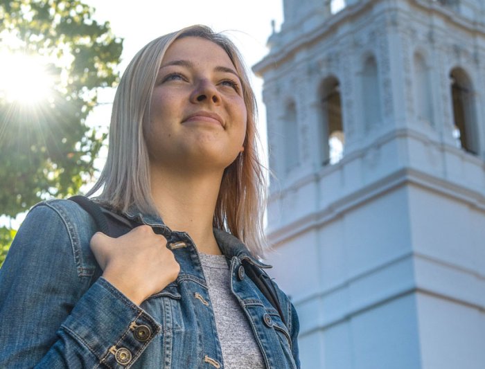 business student in front of chapel smiling