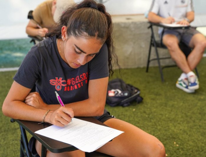 student writing on paper sitting in desk