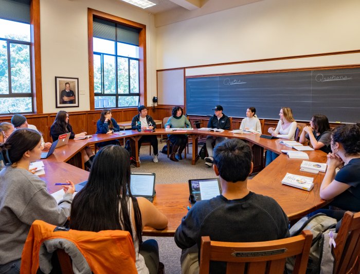 Prof. Emily Klein leads a Collegiate Seminar class which is seated around the table