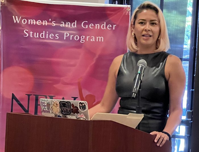 Lila Carrillo in front of a sign that says Women's and Gender Studies Program