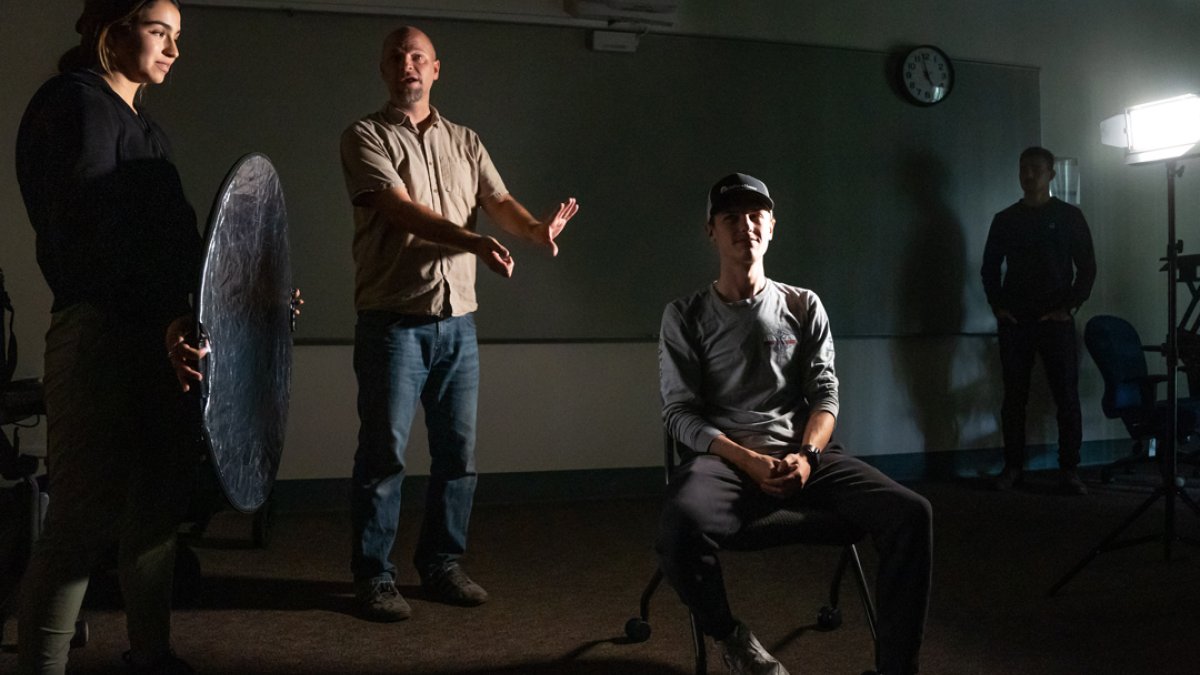 A teacher demonstrating how to light a subject in a lighting class
