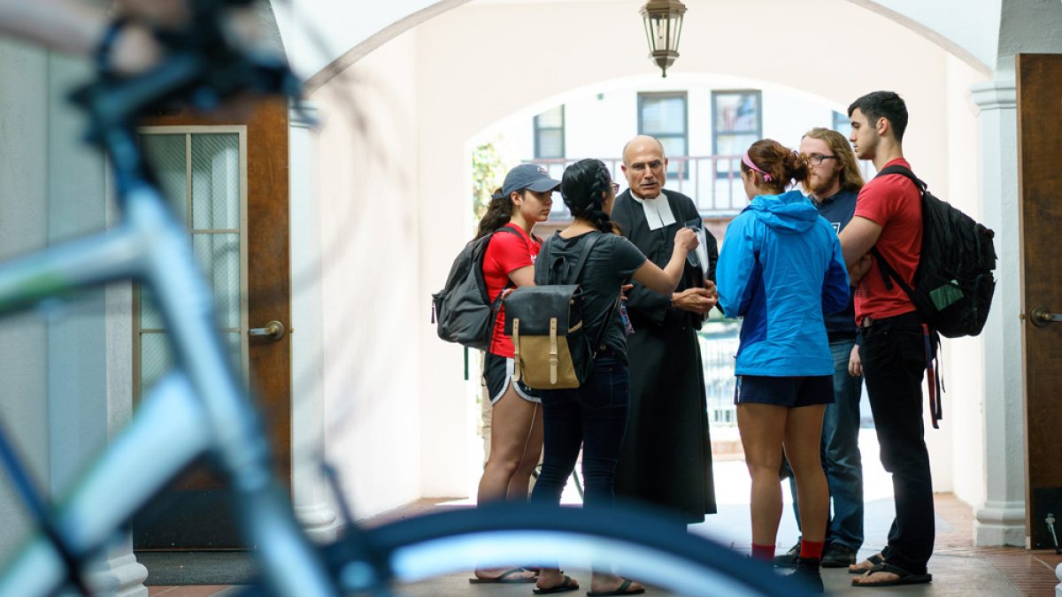brother speaking with students in hallway with bike in foreground