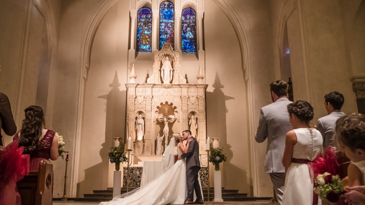 Image of a couple celebrating their first kiss at their marriage in the SMC Chapel surrounded by guests